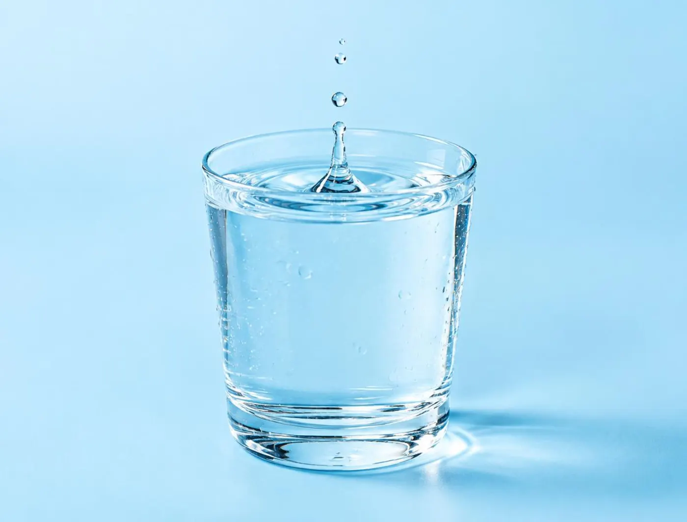Vaso de agua clara con una gota cayendo